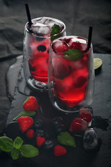 Two glasses infused water with various berry ice cubes