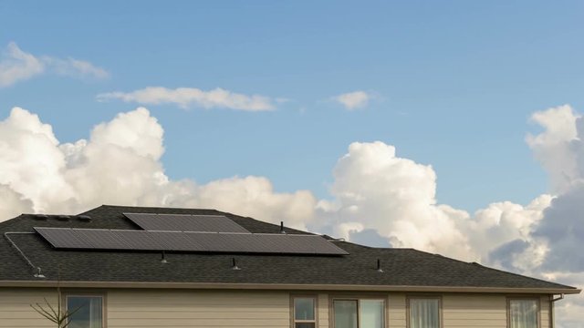 Timelapse movie of white clouds and blue sky over a north America home with a Solar Panel system installed on the rooftop 4k ultra high definition