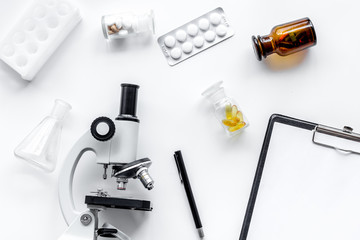 Microscope, pills and tablet on white background top view