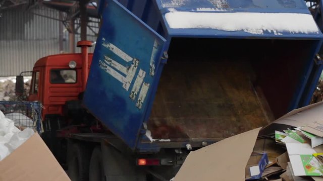 Garbage truck unloads the waste paper at the garbage recycling plant. Close-up shot. Big Factory For Recycling Paper and Carboard.