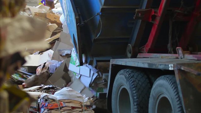 Garbage truck unloads the waste paper at the garbage recycling plant. Close-up shot. Logistics at the waste processing plant. Footage with sound. Waste paper.