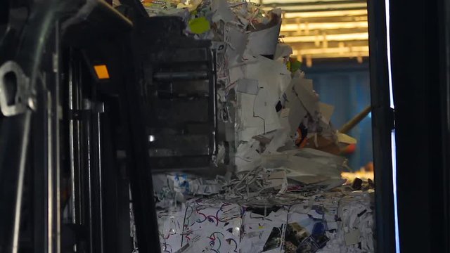 Waste paper. Loader sorts the pallets with the recycled material at the waste processing plant. Large warehouse of waste paper in a factory. Footage with sound.