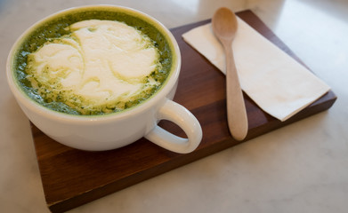 Hot green tea latte and milk froth in white cappuccino Placed on a wooden tray in a coffee shop.Close up
