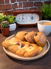 Coffee and Bread for breakfast with cactus with alarm clock placed on the side with sunlight.