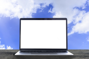 Laptop with white blank screen on wooden table and blue sky background. Computer data backup to cloud computer concept.