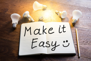 Notebook With Glowing Light Bulbs On Wooden Desk