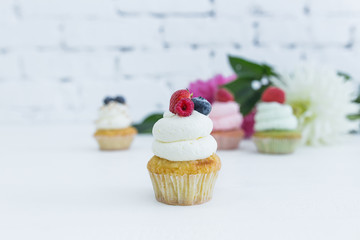 Various cupcakes with fresh berries flowers and leaves.