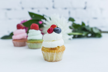 Various cupcakes with fresh berries flowers and leaves.
