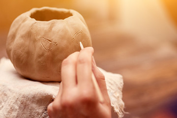 Close-up Beautiful Woman Artist Painting Pumpkin Pumpkin from Clay for Halloween on a wooden table in the workshop, preparing for  Halloween