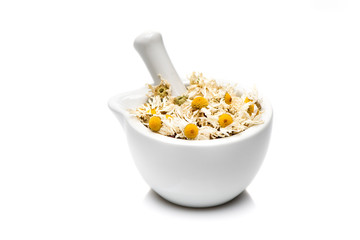 .Dried chamomile flowers in mortar on white background