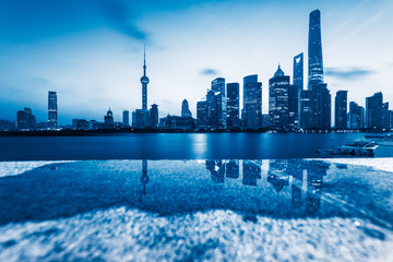 the bund skyline reflected in water puddle,shanghai,china.