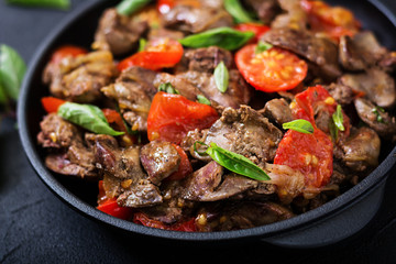 Chicken liver (offal) with onions and tomatoes in a frying pan in Armenian