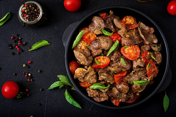 Chicken liver (offal) with onions and tomatoes in a frying pan in Armenian. Flat lay. Top view