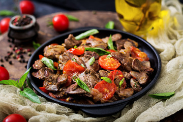Chicken liver (offal) with onions and tomatoes in a frying pan in Armenian