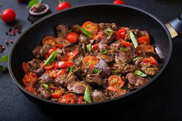 Chicken liver (offal) with onions and tomatoes in a frying pan in Armenian