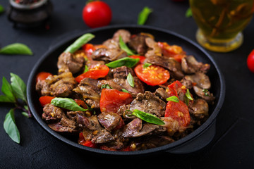 Chicken liver (offal) with onions and tomatoes in a frying pan in Armenian