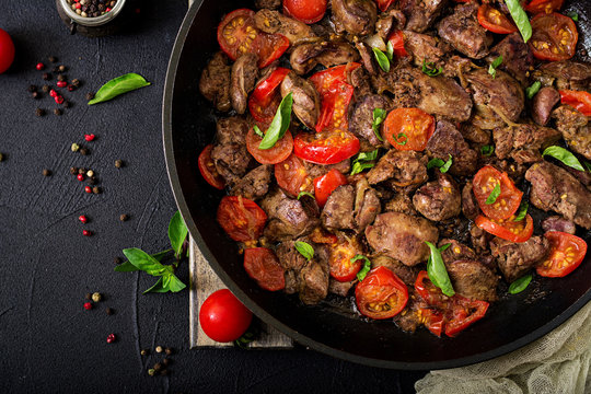 Chicken liver (offal) with onions and tomatoes in a frying pan in Armenian. Flat lay. Top view
