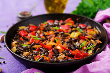 Stewed black beans with sweet peppers and tomatoes with spicy sauce in a pan.