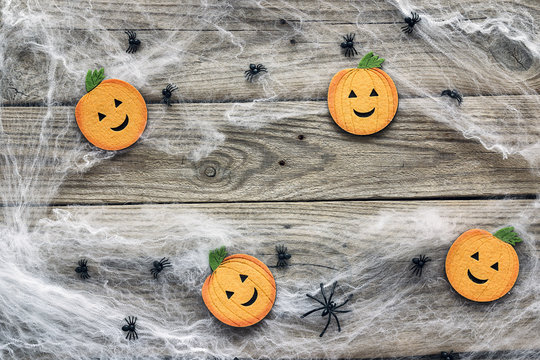 Halloween background with decorative pumpkins, creepy web and spiders on old wooden boards. Blank space for text.