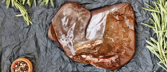 healthy fod Raw liver with rosemary on a black background