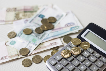 Money concept. Calculator with coins on wooden table