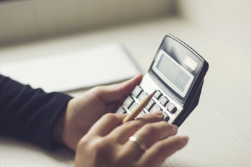 female hands counting on calculator and holding a pencil