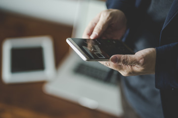 Top angle and closeup view  of businessman using the smartphone with blur laptop and digital pad background .