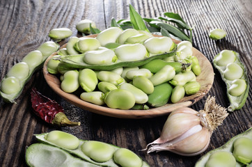 Raw  broad beans in a bowl on a wooden background