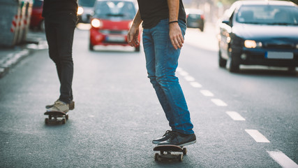 Two pro skateboard rider ride skate through cars on street