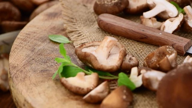 Raw Shiitake mushrooms on a rotating wooden plate (seamless loopable; 4K)