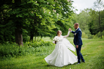 Wedding couple dancing on the meadow on a beautiful spring sunny day.