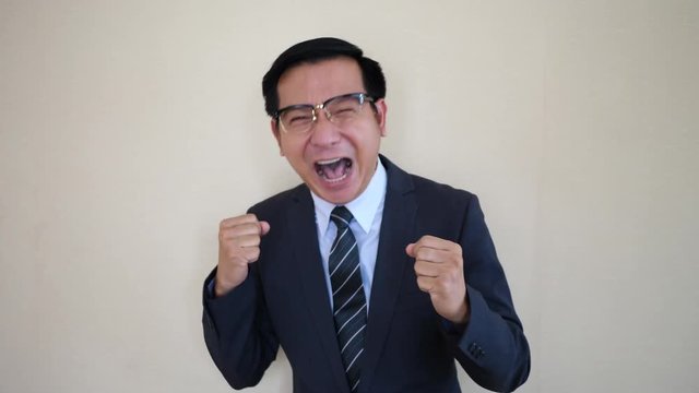 Portrait of major businessman with glasses laughing in front of camera.