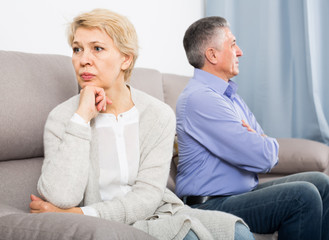 sad middle-aged couple quarreling at home with each other