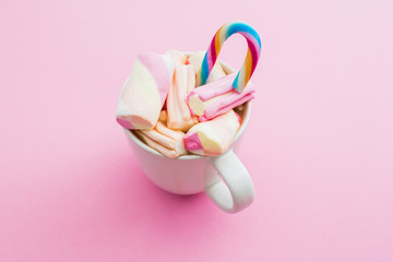 Cappuccino mug with marshmallow and cane sugar on pink background. Flat lay, top view