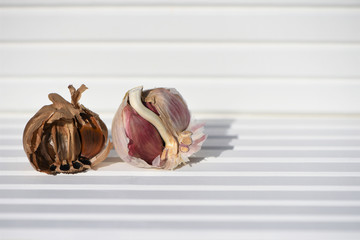 photography image black and white garlic bulb cloves on bright white wood background taken on South coast England UK