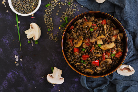 Delicious lentils with pepper and mushrooms on dark background