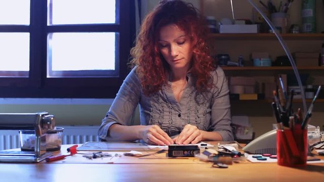 Beautiful women making polymer clay jewelry with her hands in a small workshop. Unique accessories for ladies / Women making polymer clay jewelry