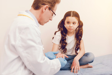 Upset kid crossing legs while being in consulting room