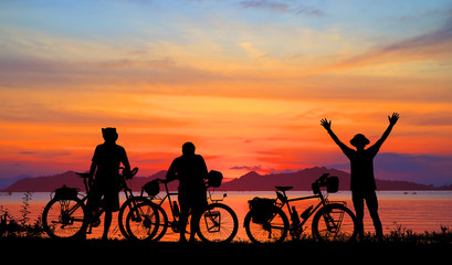 Silhouette man and bike relaxing with  colorful sunrise background.