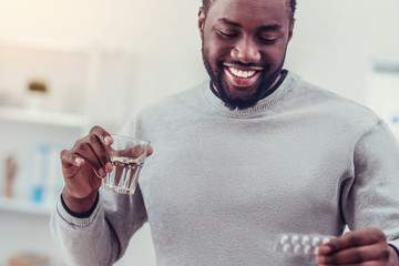 Positive minded African American man taking medication - obrazy, fototapety, plakaty