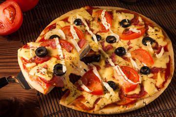 Hot pizza slice with melting cheese on a rustic wooden table