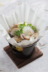 Japanese Clam Soup with Clear Broth (Asari no ushiojiru) with sliced Japanese scallion and coriander served in hot paper bowl on washi (Japanese paper). 