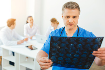 Confident millennial radiologist looking at x ray scan of patient