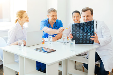Obraz premium Cheerful medical professionals counseling over MRI scan image at work