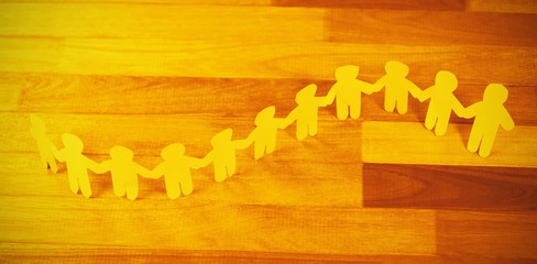 Yellow paper cutout human chain on wooden table