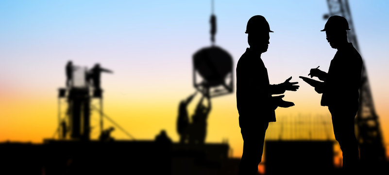  silhouette portrait of engineer Work order in construction site on blurry colorful light sunset.