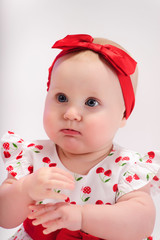 Little girl in white with a red dress with a bow on her head