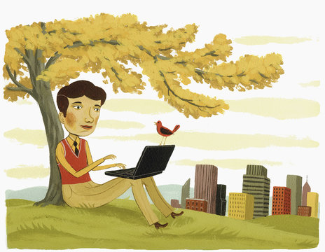 Businessman using laptop under tree