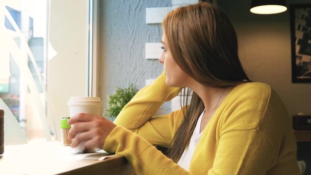 Woman with coffee look through window 