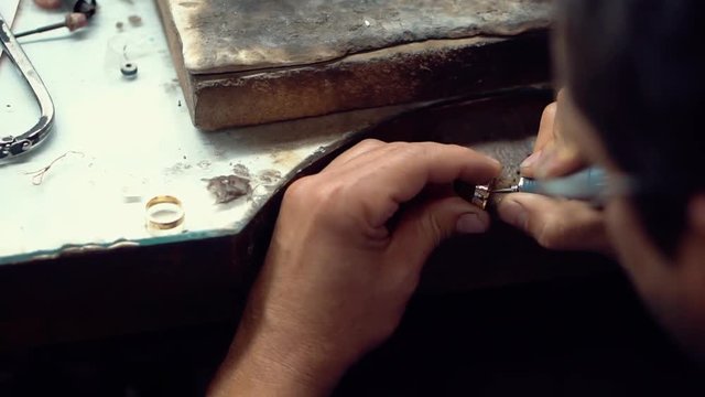  Jeweler writing name of the couple in the wedding ring, hands working with jewelry